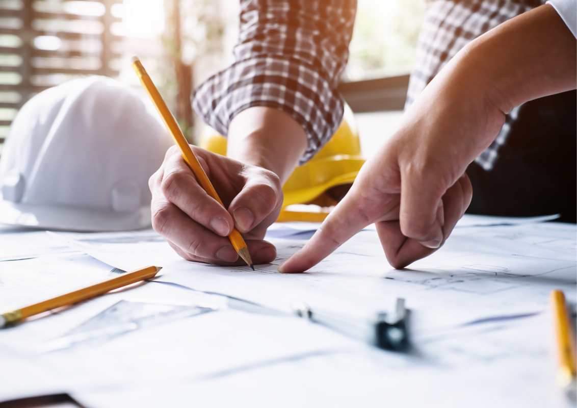 plan de travaux mains tenant un crayon et casque de chantier