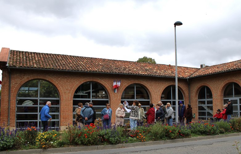 Groupe de séniors face à une guide devant la mairie